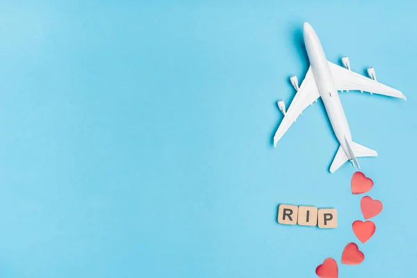 Top view of plane model, word rip and red hearts on blue background — Stock Photo