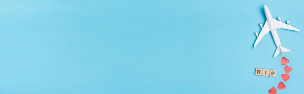 Top view of plane model, word rip and red hearts on blue background, banner — Stock Photo