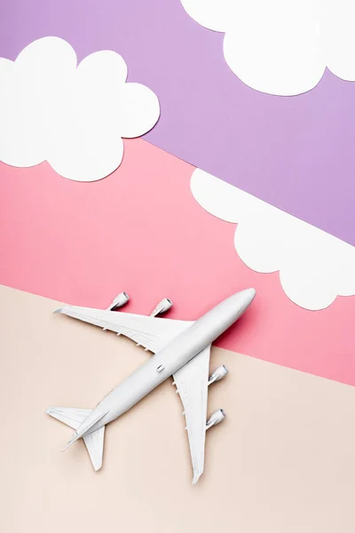 Top view of white plane model on colorful background with clouds — Stock Photo