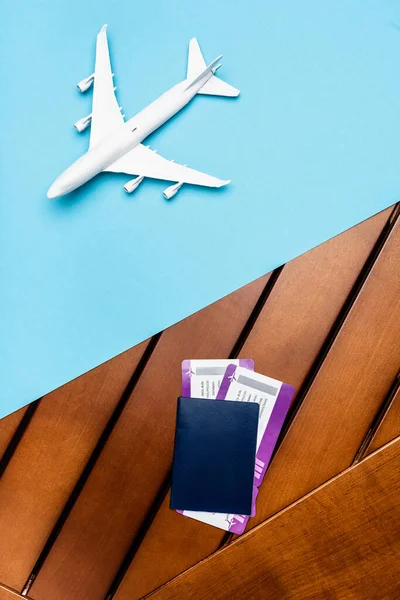 Top view of white plane model and tickets on blue and wooden background — Stock Photo