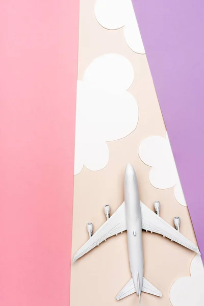 Top view of white plane model on colorful background with clouds — Stock Photo