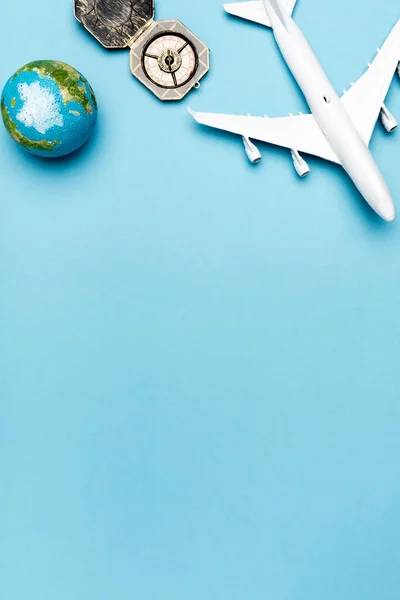 Top view of white plane model, compass, globe on blue background — Stock Photo