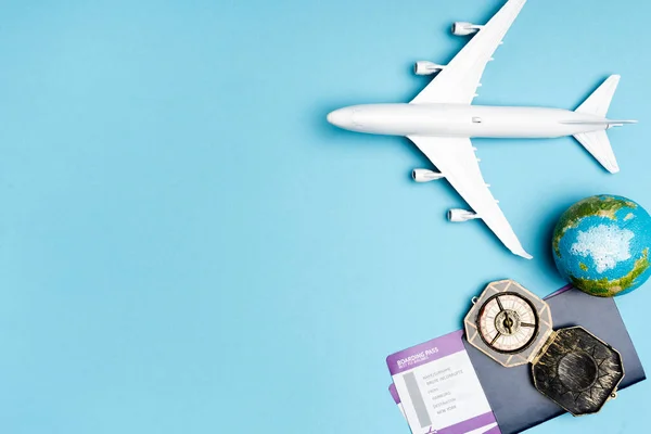 Vue du dessus du modèle d'avion blanc, boussole, globe et billets sur fond bleu — Photo de stock