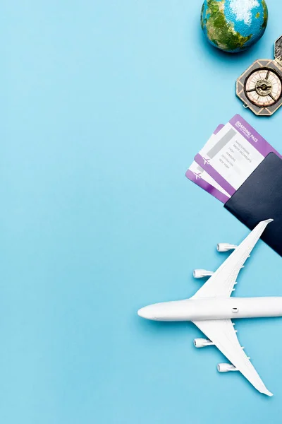 Draufsicht auf weißes Flugzeugmodell, Kompass, Globus und Tickets auf blauem Hintergrund — Stockfoto