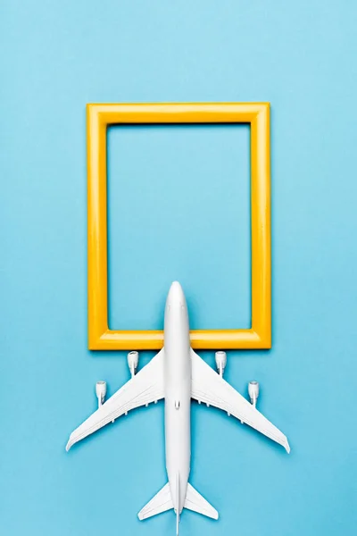 Top view of white plane model and empty frame on blue background — Stock Photo