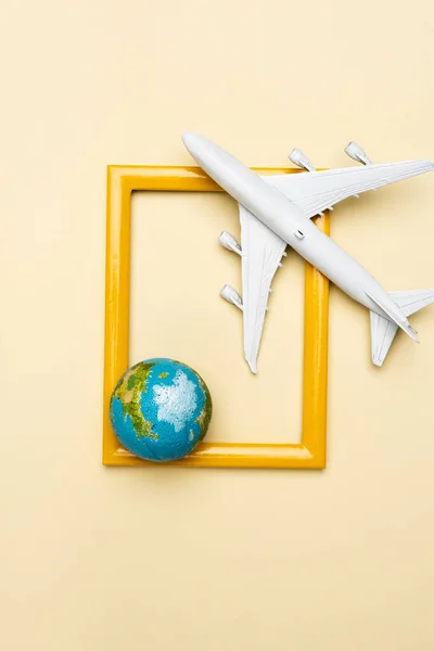 Top view of white plane model, globe and empty frame on yellow background — Stock Photo