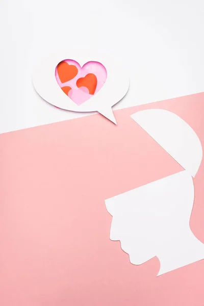 Vista dall'alto della bolla vocale con cuori e testa umana su sfondo bianco e rosa — Foto stock