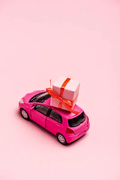 Carro de brinquedo e caixa de presente no fundo rosa — Fotografia de Stock