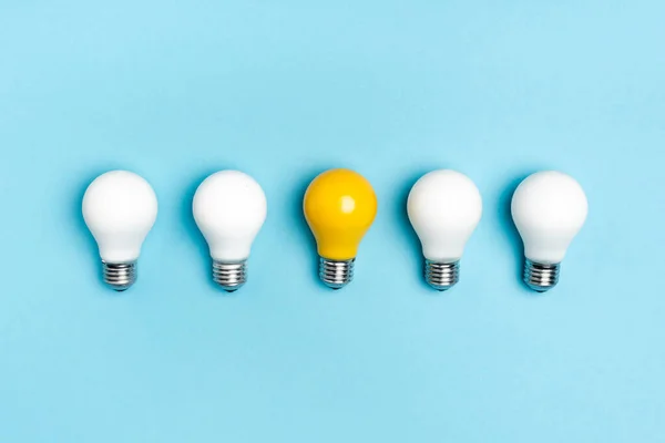 Top view of white and yellow light bulbs on blue background — Stock Photo
