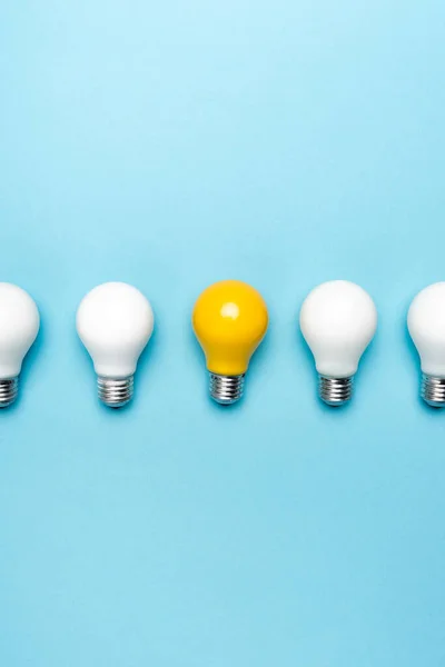 Top view of white and yellow light bulbs on blue background — Stock Photo