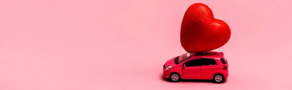 Іграшковий автомобіль і червоне серце на рожевому фоні, банер — стокове фото