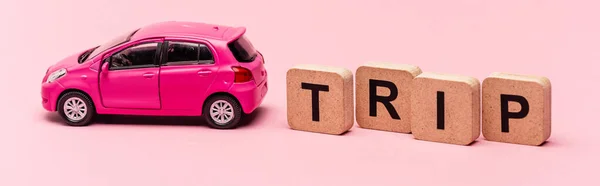 Машина и слово поездки на кубиках на розовом фоне, баннер — стоковое фото
