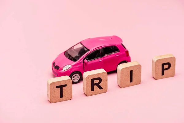 Viaje coche y palabra en cubos sobre fondo rosa — Stock Photo