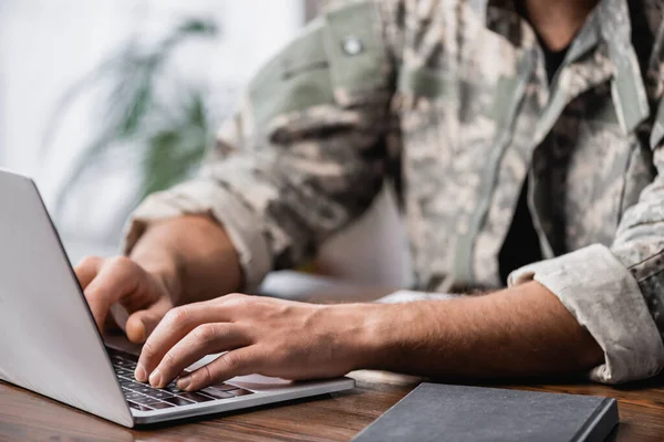 Cropped view of military man using laptop on desk — Stock Photo