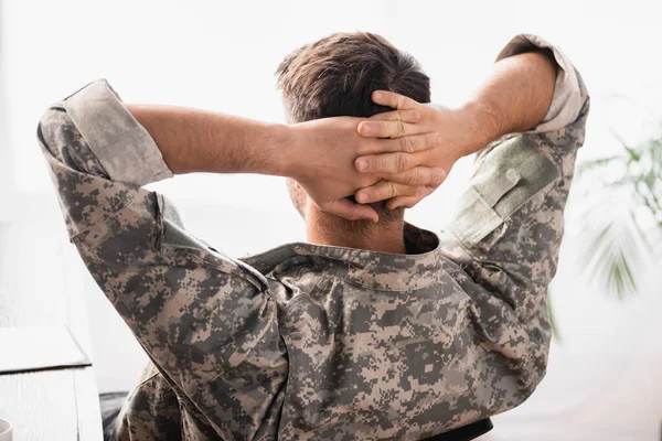 Vista trasera del soldado en uniforme militar con las manos detrás de la espalda descansando en la oficina — Stock Photo