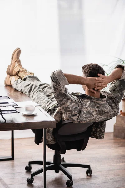 Вид ззаду військовослужбовця в уніформі з руками позаду, відпочиваючи в офісі — стокове фото