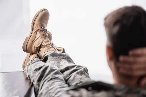 Bottes militaires sur soldat reposant sur le premier plan flou — Photo de stock