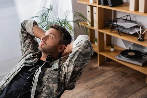 Soldato in uniforme militare e auricolare appoggiato sulla sedia — Foto stock