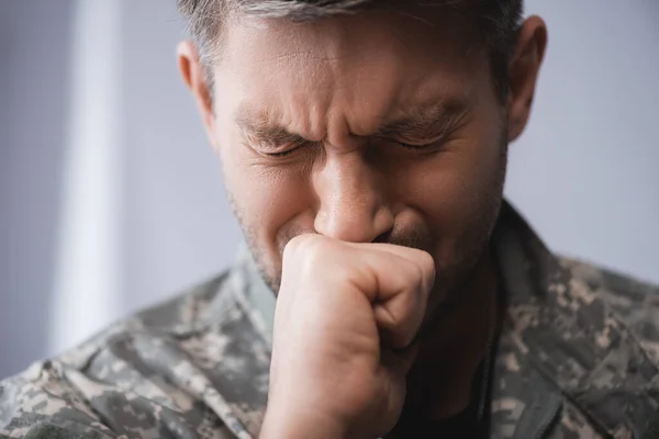 Soldado en uniforme militar llorando con los ojos cerrados - foto de stock