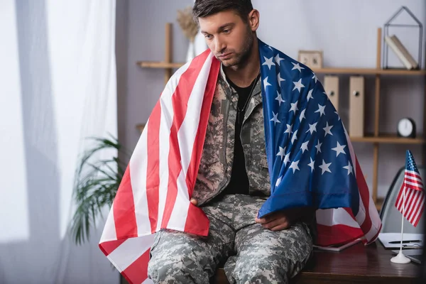 Homem militar triste envolto na bandeira americana no escritório — Fotografia de Stock