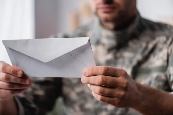 Enveloppe blanche dans les mains de l'homme militaire sur fond flou — Photo de stock