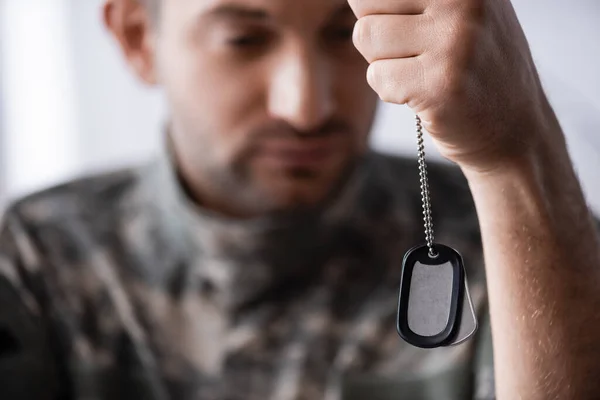 Militäretikett in der Hand auf Soldat auf verschwommenem Hintergrund — Stockfoto