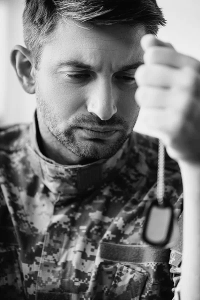Soldado triste em camuflagem uniforme segurando tag militar, monocromático — Fotografia de Stock