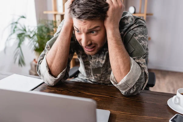 Stressed military man looking at laptop in office — Stock Photo