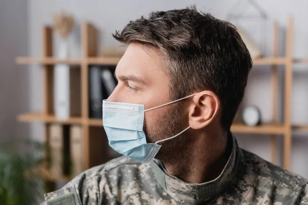 Військовий чоловік в уніформі та медичній масці дивиться геть — стокове фото