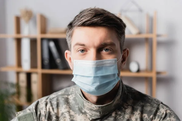 Militar en uniforme y máscara médica mirando a la cámara - foto de stock