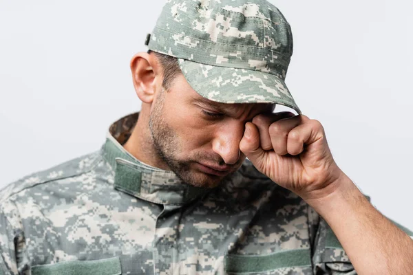 Triste uomo militare in uniforme e tappo asciugare le lacrime mentre piangeva isolato su bianco — Foto stock