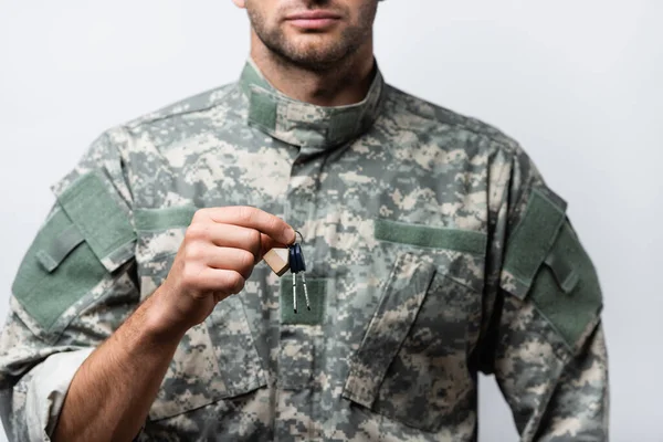 Vista recortada del militar patriótico en uniforme sosteniendo llaves aisladas en blanco - foto de stock