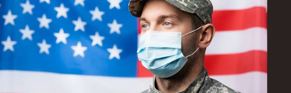 Uomo militare in uniforme e maschera medica vicino bandiera americana su sfondo sfocato, banner — Foto stock