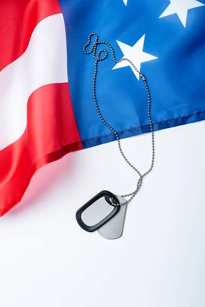 Emblema metálico em branco na cadeia perto da bandeira americana no branco — Fotografia de Stock