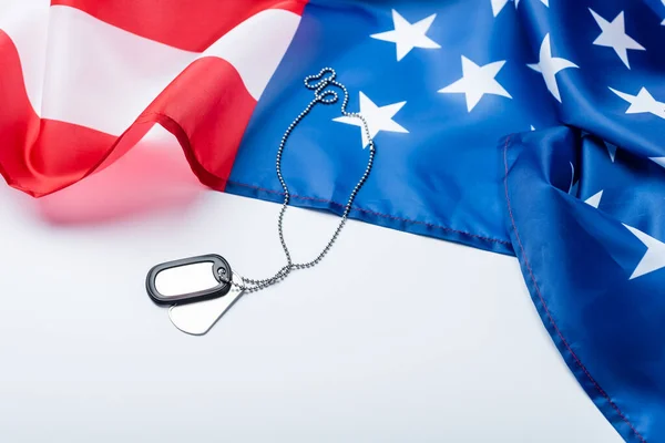 Unbeschriebenes silbernes Abzeichen an Kette nahe der amerikanischen Flagge auf weiß — Stockfoto