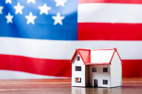 House model on wooden desk near american flag on blurred background — Stock Photo