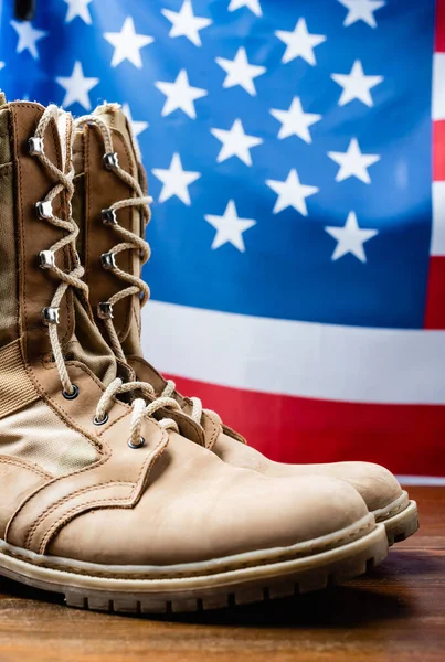 Stivali militari vicino bandiera americana su sfondo sfocato — Foto stock