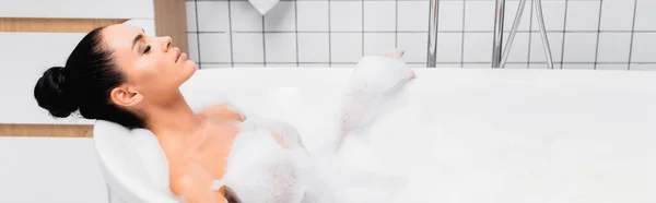 Jeune femme relaxant tout en prenant un bain avec de la mousse, bannière — Photo de stock