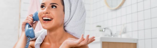 Веселая женщина с полотенцем на голове говорит по телефону в ванной комнате на размытом фоне, баннер — стоковое фото
