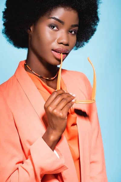 Mujer joven afroamericana en traje elegante naranja aislado sobre fondo azul - foto de stock
