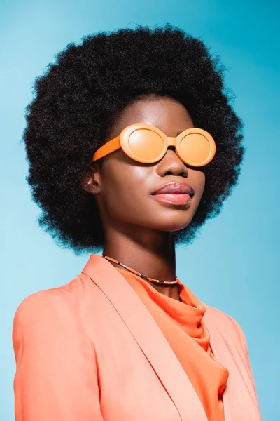 Mujer joven afroamericana en traje elegante naranja aislado sobre fondo azul - foto de stock