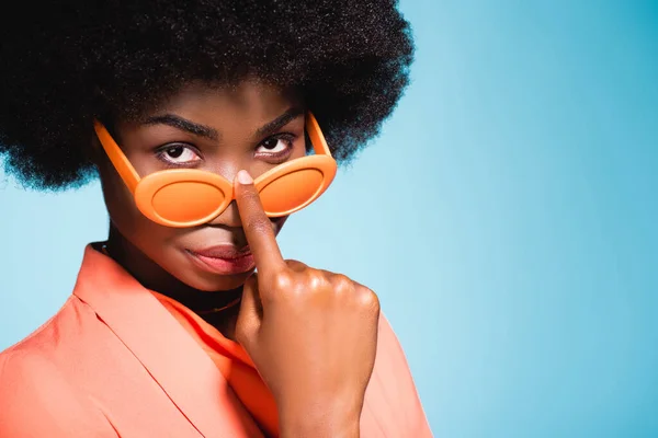 African american young woman in orange stylish outfit isolated on blue background — Stock Photo