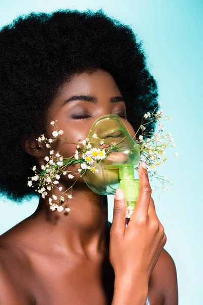 Jovem afro-americana com flores em inalador isolado em fundo azul — Fotografia de Stock