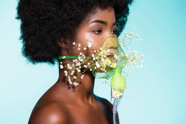 Afro-américaine jeune femme avec des fleurs dans inhalateur isolé sur fond bleu — Photo de stock