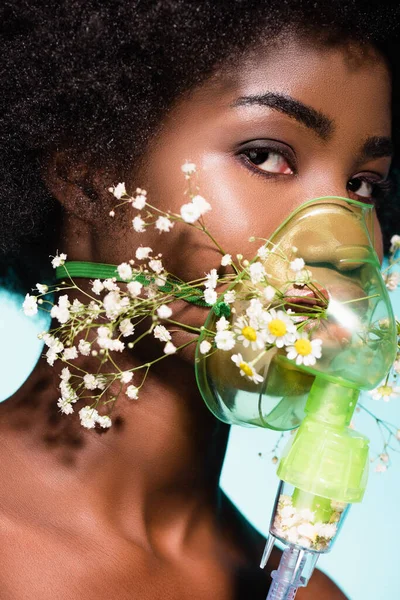 Afro-américaine jeune femme avec des fleurs dans inhalateur isolé sur fond bleu — Photo de stock