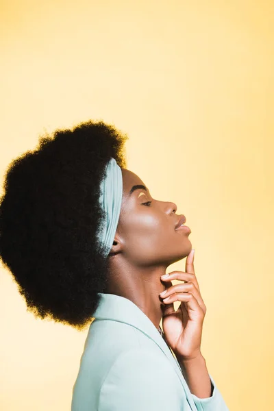 Side view of african american young woman in blue stylish outfit isolated on yellow — Stock Photo