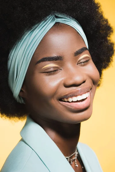 Laughing african american young woman in blue stylish outfit isolated on yellow — Stock Photo