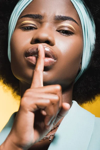 Africano americano jovem mulher em azul elegante roupa mostrando shh isolado no amarelo — Fotografia de Stock