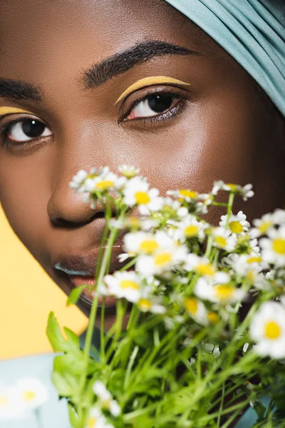 Close-up da jovem americana africana com buquê de camomila isolado no amarelo — Fotografia de Stock