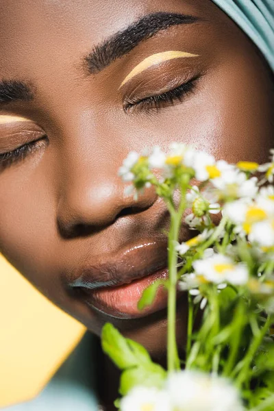 Nahaufnahme einer jungen afrikanisch-amerikanischen Frau mit Kamillenstrauß isoliert auf gelb — Stockfoto